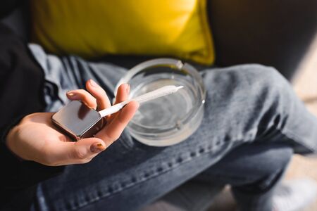 cropped view of girl holding lighter, marijuana joint and ashtray 