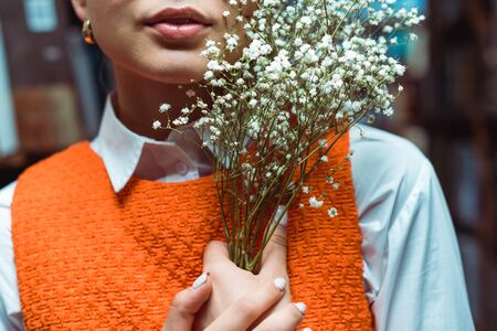 cropped view of young adult woman holding white flowersの写真素材