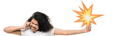 panoramic shot of emotional african american girl with closed eyes covering ear and holding comic...