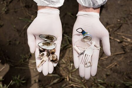 cropped view of ecologist in latex gloves holding plastic garbage and