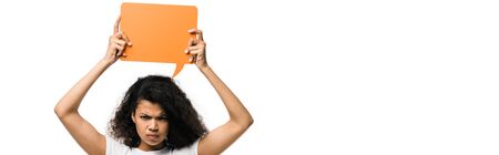 panoramic shot of angry african american girl holding orange speech bubble isolated on whiteの写真素材
