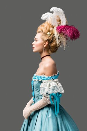 side view of elegant victorian woman in wig and blue dress isolated on greyの写真素材