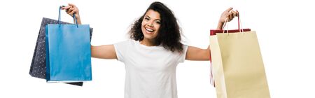 panoramic shot of cheerful african american girl holding shopping bags isolated on white