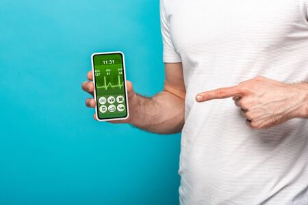 cropped view of man pointing at smartphone with health app, isolated on blue