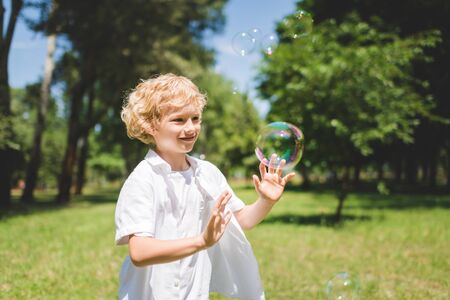 adorable boy Gesturing near soap bubbles in parkの写真素材