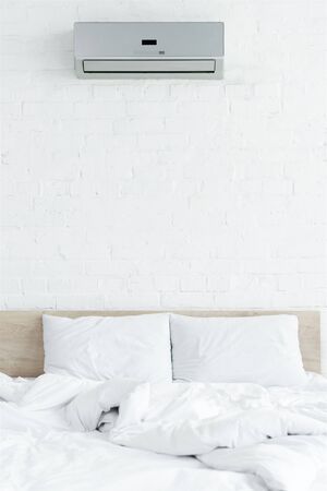 white bedroom with brick wall, bed and air conditionの写真素材