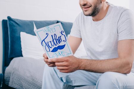 cropped view of smiling bearded man holding handmade fathers day greeting card