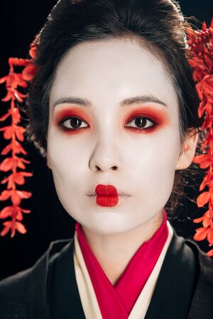 portrait of beautiful geisha with red eyeshadow and lips isolated on blackの写真素材
