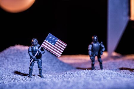 selective focus of toy astronauts holding american flag in spaceの写真素材