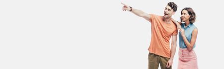 panoramic shot of cheerful woman standing near smiling man pointing with finger isolated on greyの写真素材