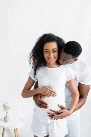 calm african american man hugging with pregnant wifeの写真素材