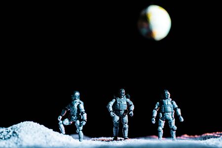 toy soldiers standing on planet in space on black background with planet earthの写真素材