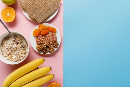 top view of fresh fruits, crispbread and breakfast cereal on blue and pink background with copy...