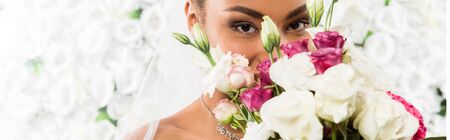 panoramic shot of african american bride covering face with flowersの写真素材