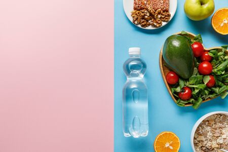 top view of bottle with water and diet food on blue and pink backgroundの写真素材