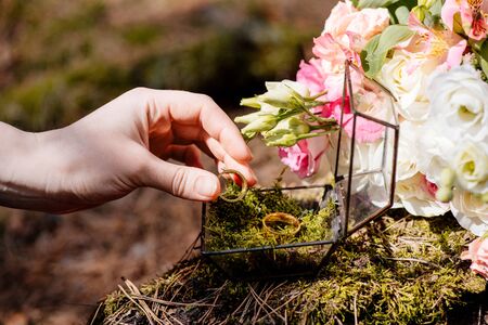cropped view of bride with flowers and wedding rings