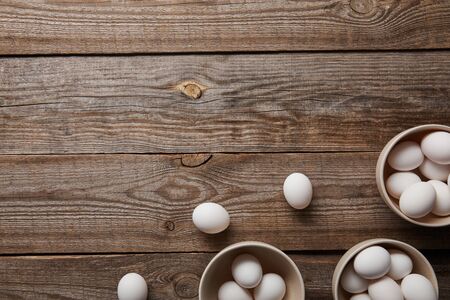 top view of chicken eggs in bowls on wooden tableの写真素材