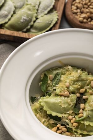 close up view of tasty green ravioli served in plate with sage, pine nuts and grated cheeseの写真素材