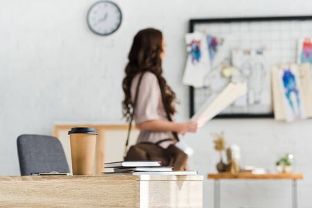 selective focus of paper cup near notebooks and curly womanの写真素材