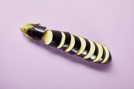 top view of ripe sliced eggplant on violet background
