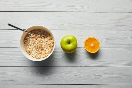 flat lay with breakfast cereal in bowl, apple, orange on wooden white backgroundの写真素材