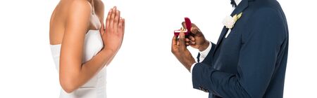 panoramic shot of african american man holding box with ring while making proposal to  woman...
