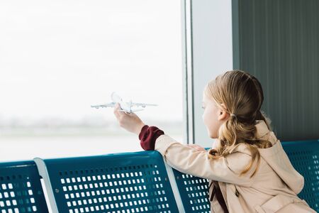 preteen kid holding toy plane in airport departure loungeの写真素材