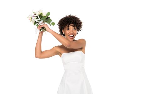 excited african american bride throwing bouquet and looking at camera isolated on whiteの写真素材