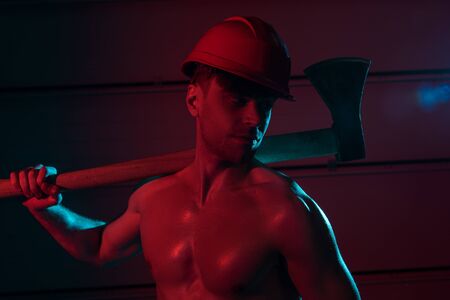 sexy shirtless fireman in protective helmet holding flat head axe in darknessの写真素材