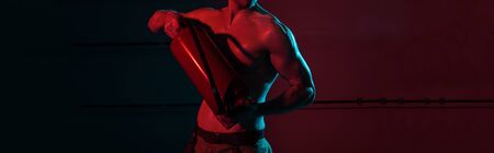 panoramic shot of sexy shirtless fireman holding fire extinguisher in darkness