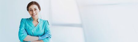 panoramic shot of cheerful latin doctor standing with crossed arms and smiling at cameraの写真素材