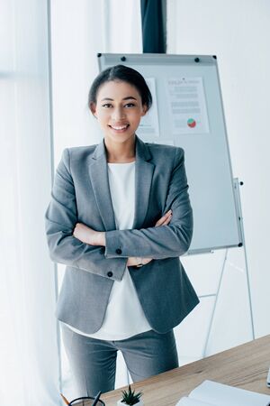 beautiful latin businesswoman standing with crossed arms and smiling at cameraの写真素材
