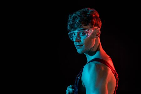 sexy fireman in overall and protective goggles isolated on blackの写真素材