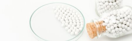 panoramic shot of bottles with pills near glass petri dish isolated on whiteの写真素材