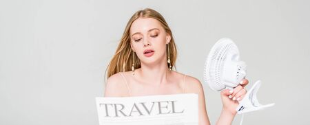 panoramic shot of young woman with Electric Fan and travel newspaper suffering from heat isolated on...