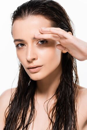 beautiful wet nude young woman with hand near face looking at camera isolated on white