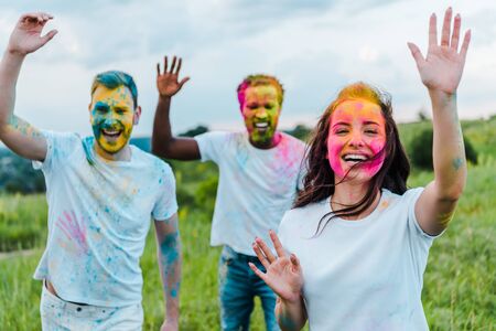 selective focus of  multicultural friends with colorful holi paints on facesの写真素材