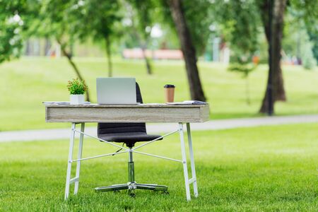 selective focus of office table with different office stuff near office chair in parkの写真素材