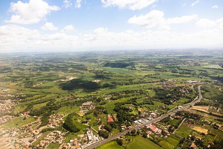 aerial view of beautiful green landscape with hills and houses under blue sky in rome, italyの写真素材