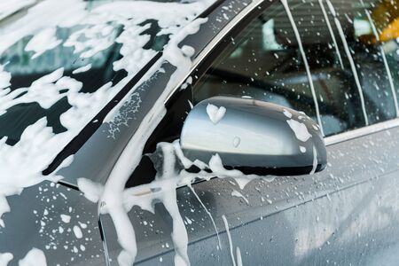 cropped view of car mirror with white foam in car washの写真素材