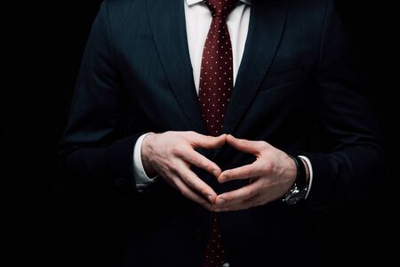 partial view of confident businessman showing steeple gesture isolated on black, human emotion and expression conceptの写真素材