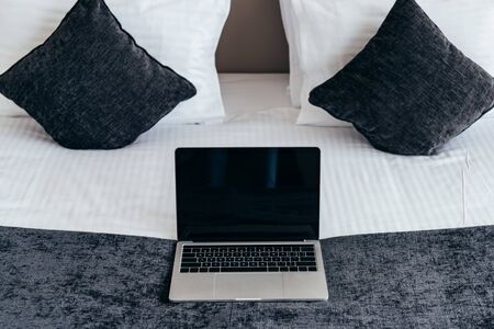 laptop with blank screen on bed in hotel roomの写真素材