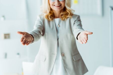 cropped view of cheerful blonde woman gesturing in officeの写真素材