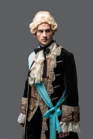 handsome victorian gentleman in wig standing isolated on greyの写真素材