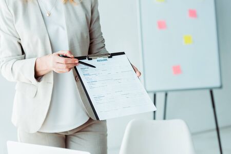cropped view of woman holding clipboard with resume lettering and penの写真素材