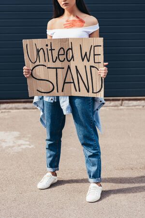 cropped view of feminist holding placard with inscription united we stand on streetの写真素材