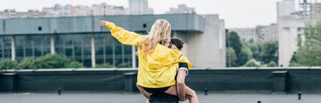back view of blonde woman playing with man on roofの写真素材