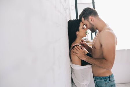 side view of sexy man hugging and kissing with brunette and passionate womanの写真素材