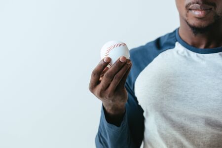 partial view of african ameriican baseball player holding ball isolated on greyの写真素材