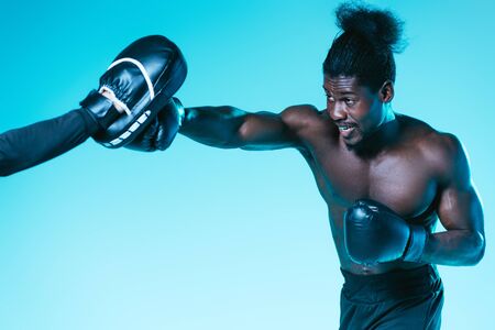 african american boxer working out with trainer on blue backgroundの写真素材